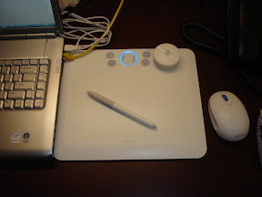 Wacom Bamboo Fun 白色放在一台电脑旁边。